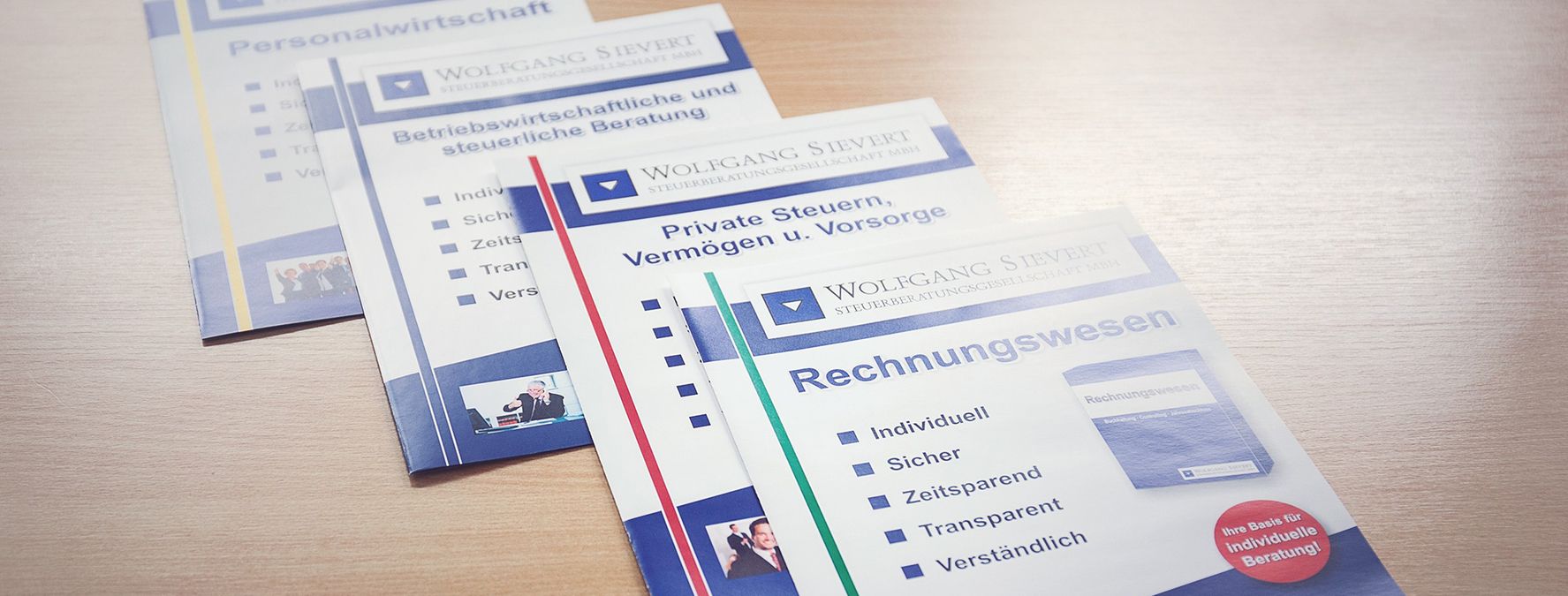 Vier verschiedene Flyer, die auf einem Holztisch liegen